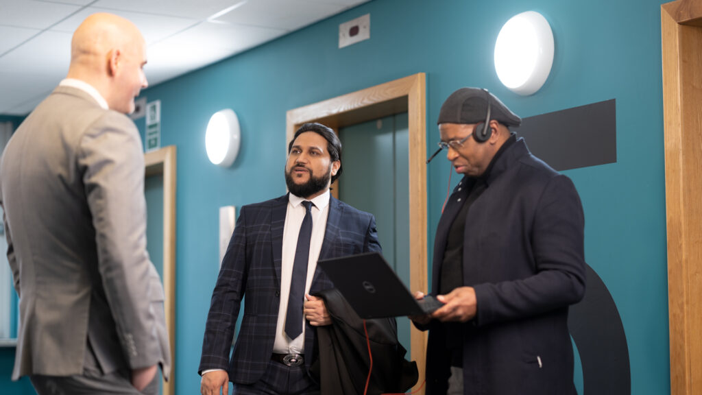 Three male members of Home Office staff one working on a laptop